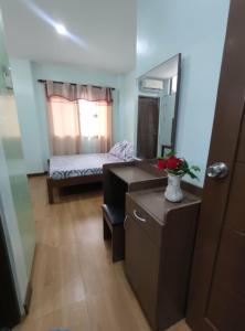 a bedroom with a bed and a desk and a mirror at GLJ Apartment in Ormoc
