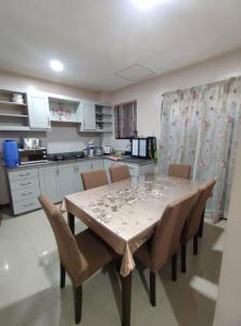 a dining room table with chairs and a kitchen at GLJ Apartment in Ormoc