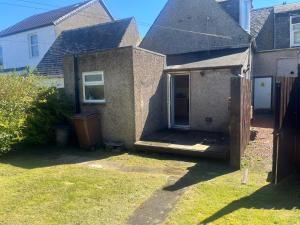 a house with a porch in a yard at Lower Mill Apartment in Newmilns