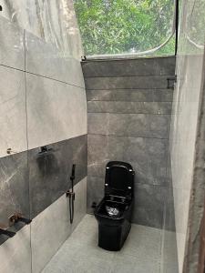 a bathroom with a black toilet and a window at Riva farmstay in Mayyanād