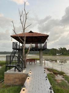 a gazebo with a bench and a tree at Riva farmstay in Mayyanād