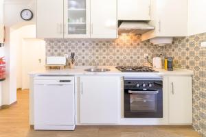 a kitchen with white cabinets and a sink at Celestial Melides Country House in Melides