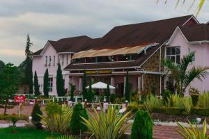 a large pink building with trees and plants at Kinyuki Country Hotel in Nanyuki