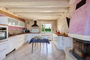 a kitchen with white cabinets and a table at Longère Pierre De Ronsard piscine in Rilly-sur-Loire