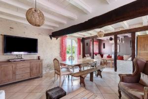 a living room with a table and a tv at Longère Pierre De Ronsard piscine in Rilly-sur-Loire