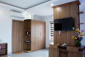 a living room with a tv on a wooden cabinet at Sunflower Hotel in Nhơn Trạch