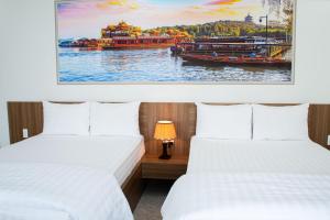 two beds in a room with a picture of a boat at Sunflower Hotel in Nhơn Trạch +34 photos