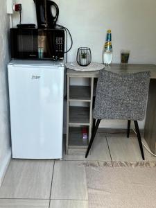 a white refrigerator next to a table and a chair at Calming Waters Guesthouse in Grahamstown