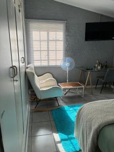 a bedroom with a bed and a chair and a table at Calming Waters Guesthouse in Grahamstown