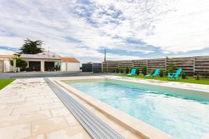 a swimming pool with two blue chairs in a yard at Gîtes Les 2 Fontaines in Marans