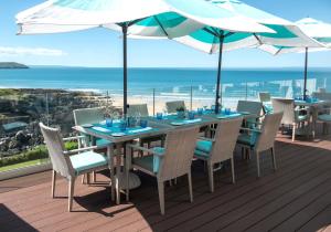 a table with chairs and an umbrella on a deck with the beach at Watersmeet Hotel in Woolacombe