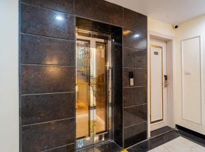 a bathroom with a shower with black tile walls at Treebo Vistara Gold Ujjain Junction in Ujjain +36 photos