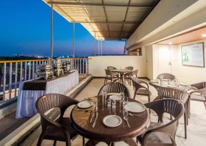 a restaurant with tables and chairs on a balcony at Treebo Vistara Gold Ujjain Junction in Ujjain