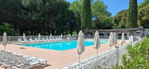 a swimming pool with chairs and umbrellas at Mobil home proche Fréjus - Camping 4 étoiles in Puget-sur-Argens
