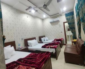 a hotel room with three beds and a couch at Second Home Hotel in Multan +49 photos