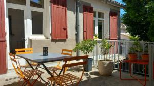 a table and chairs on a balcony with red shutters at Chez Valérie côté Sud in Saint-Jean-du-Gard