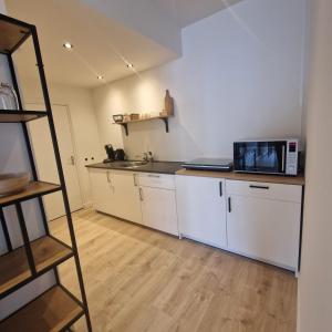 a kitchen with white cabinets and a microwave at 't Westeind, Modern en sfeervol appartement in Norg in Norg
