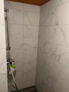 a bathroom with a shower with white marble walls at Bedi Vendégház in Nagybakónak +28 photos
