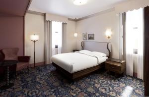 a bedroom with a bed and a desk and a chair at The Queen’s Cue, Stratford, A Tribute Portfolio Hotel in Stratford