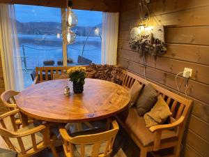 a wooden table and chairs in a room with a window at Småstranda Fjord Lodge in Åheim