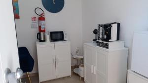 a kitchen with white cabinets and a clock on the wall at Komodo Rooms in Agropoli +21 photos