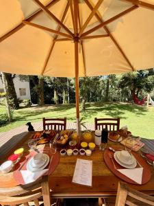 a wooden table with food on it with an umbrella at Pousada Águas do Alto in São Francisco Xavier