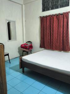 a bedroom with a bed and a red curtain at Oasis Lodge in Jorhat