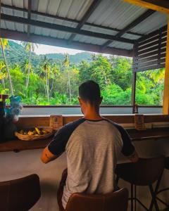 a man sitting at a table looking out a window at Koh Tao Silver Na’s Hostel in Ko Tao