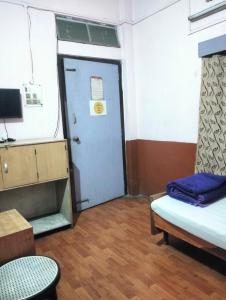a room with a door and a bed and a table at Oasis Lodge in Jorhat
