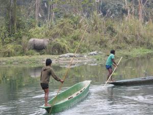 two men are rowing boats in the water at YHA Backpacker Hostel Sauraha in Sauraha