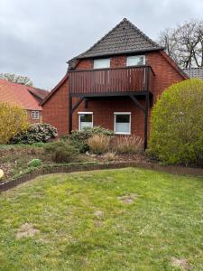 a red brick house with a deck and a yard at Ferienwohnung Hocke in Wulfsen