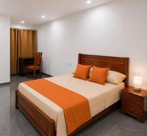 a bedroom with a bed with orange pillows and a desk at Praia City Apartments in Praia