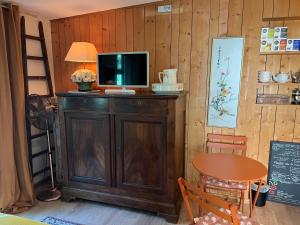 a tv on top of a wooden cabinet with a table at Bed and B Les Truffières in Trémolat