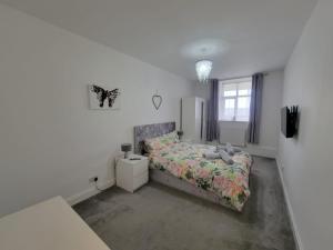 a white bedroom with a bed and a window at Cwtch y Môr - NEW Outdoor Pool Spacious 3 bed, sea & mountain views in Holy Island