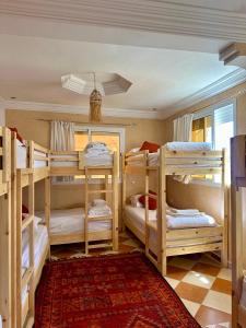 a room with four bunk beds and a rug at Tiri Hub in Tamraght Ouzdar