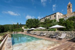 a pool with chairs and umbrellas in front of a building at Locanda dei Logi in San Gimignano