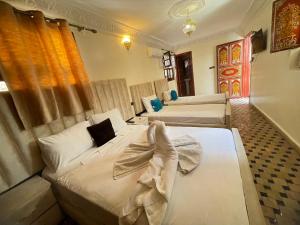 a hotel room with three beds in it at Dar El Mathaf FES El BALI in Fez
