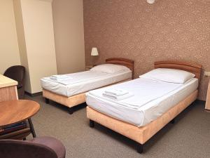 two beds in a room with a table and chairs at Noclegi-Restauracja Boss in Mogilno
