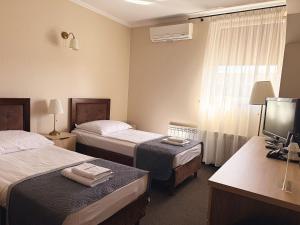 a hotel room with two beds and a television at Noclegi-Restauracja Boss in Mogilno