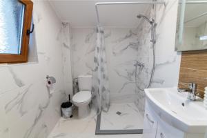 a white bathroom with a toilet and a sink at Smokinite Villa 1 - Pool and BBQ near the beach in Varna City +7 photos