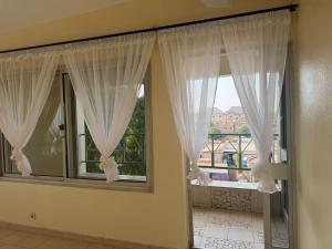 a room with two large windows with white curtains at Lilia Business Hotel in Ouagadougou
