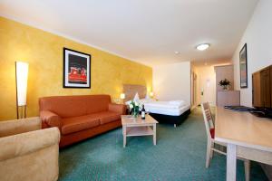 una camera d'albergo con un divano e un letto di Das Hotel Eden - Das Aktiv- & Wohlfühlhotel in Tirol auf 1200m Höhe a Seefeld in Tirol