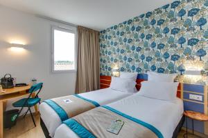 a hotel room with two beds and a desk at Sure Hotel by Best Western Sarlat-la-Canéda in Sarlat-la-Canéda +62 photos