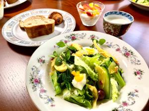 a plate of food with a salad and bread on a table at 国登録有形文化財の宿 Hotel 旧若林邸 in Sado