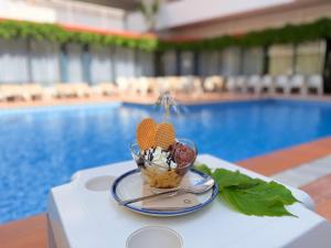 a bowl of ice cream on a table next to a pool at Hotel Xaine Park in Lloret de Mar