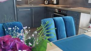 a kitchen with blue chairs and a table with flowers at Ferienwohnung Boddenblick-Vilm in Putbus