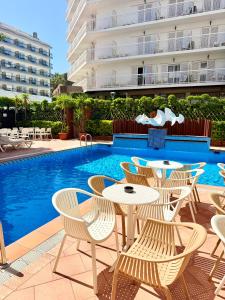 a patio with tables and chairs next to a swimming pool at Hotel Xaine Park in Lloret de Mar