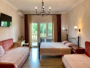 Guesthouse-villa Shekvetili AE في شيخفيتيلي: غرفة نوم بها سريران وأريكة وثريا