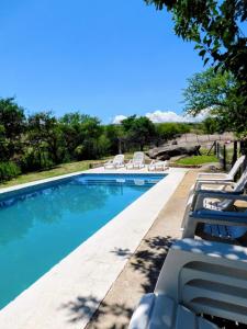 a swimming pool with chaise lounge chairs next to it at Rancho Escondido in Mina Clavero