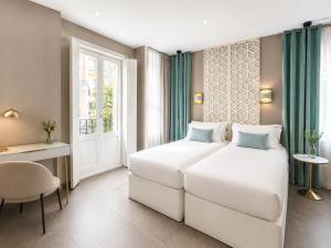 a bedroom with a white bed and a desk and a window at Abalú Collection Suites Gran Via in Madrid